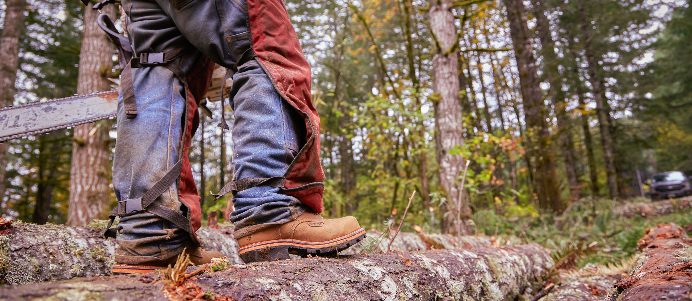 A man wearing Chippewa Super DNA work boots while standing on a log.
